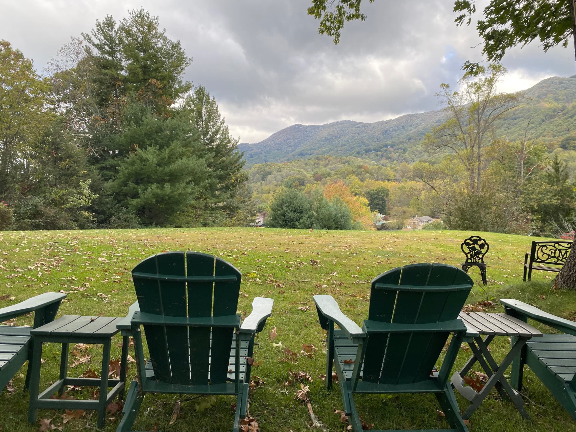 Chairs face a scenic view of mountains and trees under a cloudy sky. Chairs face a scenic view of mountains and trees under a cloudy sky.
