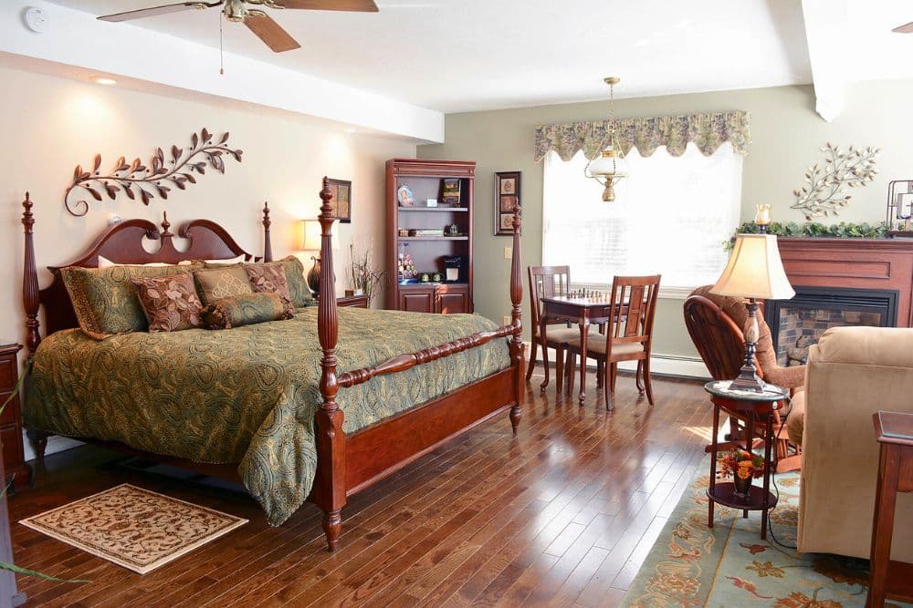 Cozy bedroom with a large bed, wooden furniture, and a small dining area by the window.